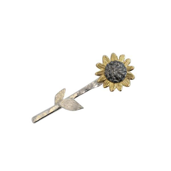 Sunflower-shaped brooch with gold and silver design on a white background