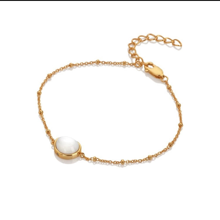 Gold bracelet with a white pearl on a white background