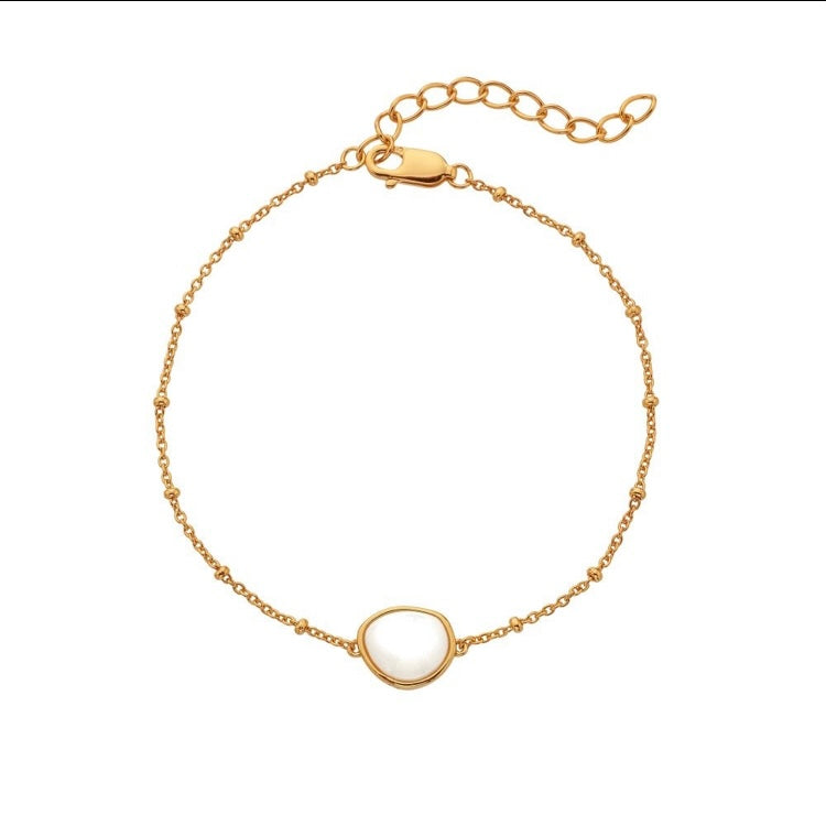 Gold bracelet with a circular charm on a white background