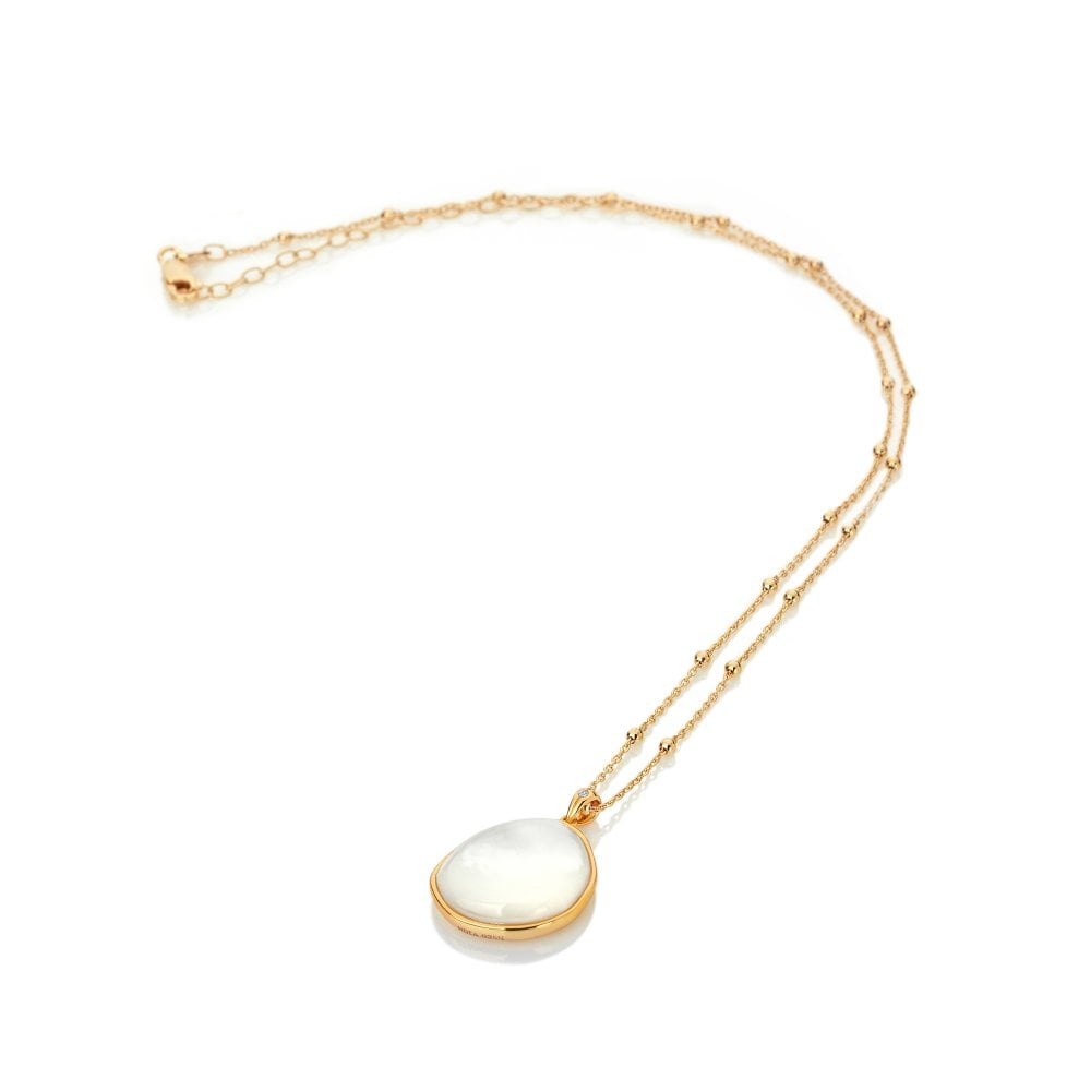 Gold necklace with a white pendant on a white background
