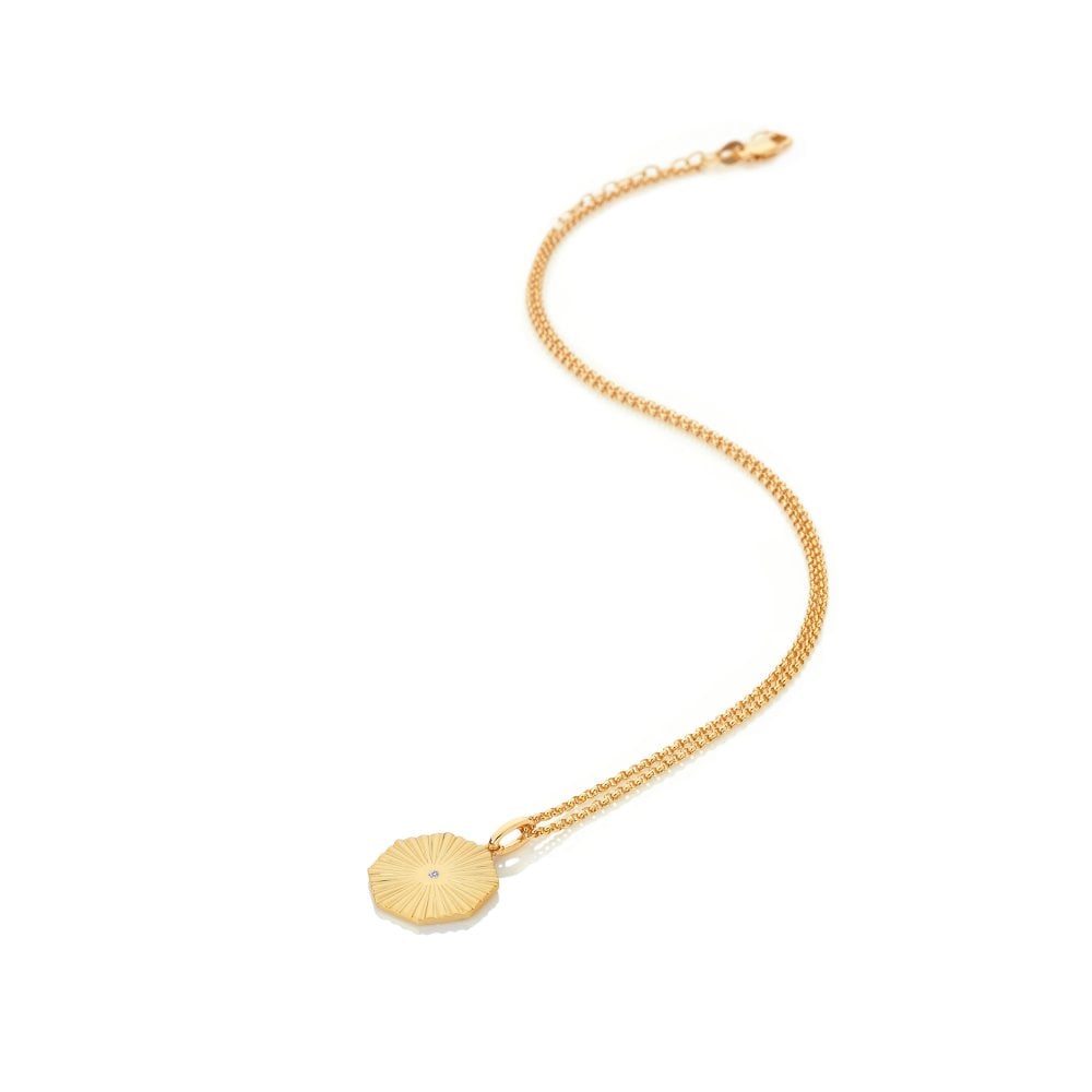 Gold bracelet with a round pendant on a white background
